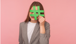 Woman holding hashtag over face against pink background